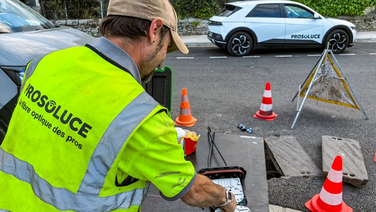 Technicien Prosoluce raccordant une fibre optique dans une chambre de tirage, en bord de route
